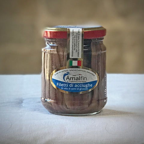 A glass jar of umami-rich Villa Cappelli Amalfi anchovy fillets in sunflower oil on a table, clear frontal view with focus on the label.