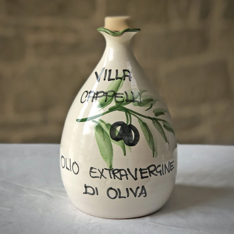 A white ceramic jug with a green branch and black text by Villa Cappelli Ceramic Oil Dispenser.