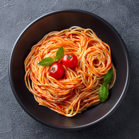 A bowl of spaghetti with Villa Cappelli Passata (Strained Tomatoes) and basil.