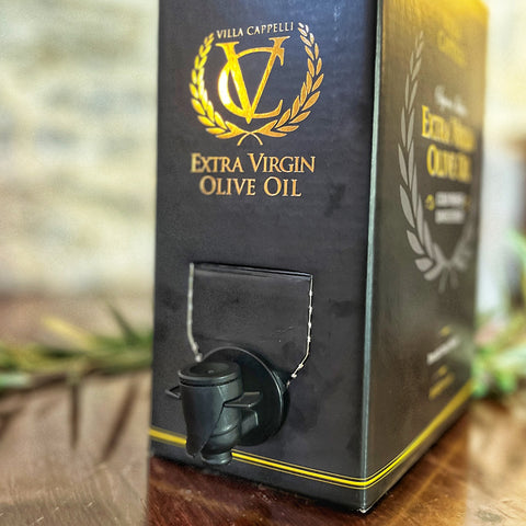 A close-up of the Villa Cappelli 3L Extra Virgin Olive Oil box with a spout sits on a wooden surface.