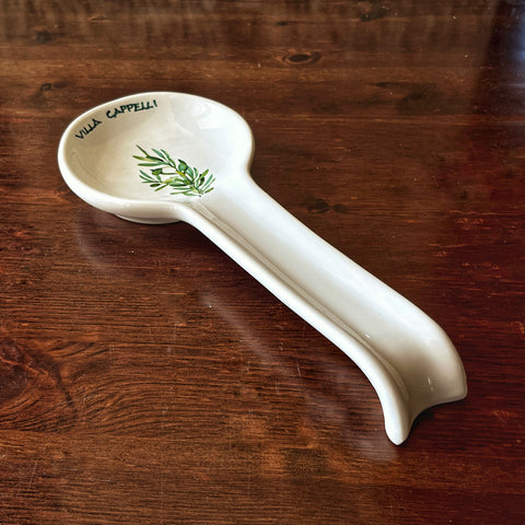 The Pausa Perfetta spoon rest by Villa Cappelli is a white, handcrafted piece from Puglia, featuring an olive branch and "VILLA CAPPELLI" text—ideal for your Italian cooking.