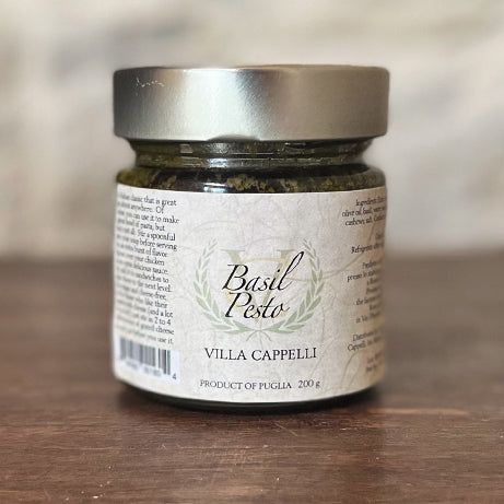 A jar of Villa Cappelli Basil Pesto Collection on a wooden table.