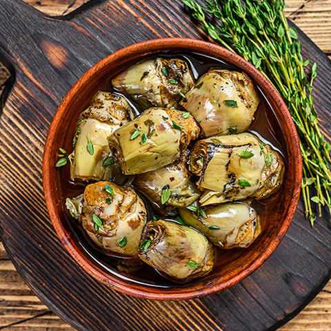 Marinated Artichoke Hearts in a bowl on a wooden table from Villa Cappelli.