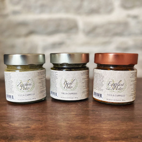 Three jars of Villa Cappelli Pesto Collection on a wooden table.