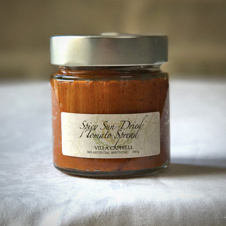 A jar of Villa Cappelli Spicy Sun-Dried Tomato Spread sits on a table.