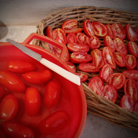 A red bowl of The Easy Italian Collection tomatoes next to a knife, perfect for Italian cooking.