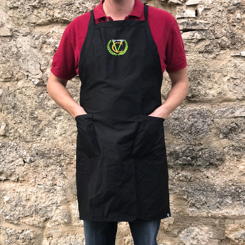 A man wearing a Villa Cappelli Cross-Back Apron standing in front of a stone wall.
